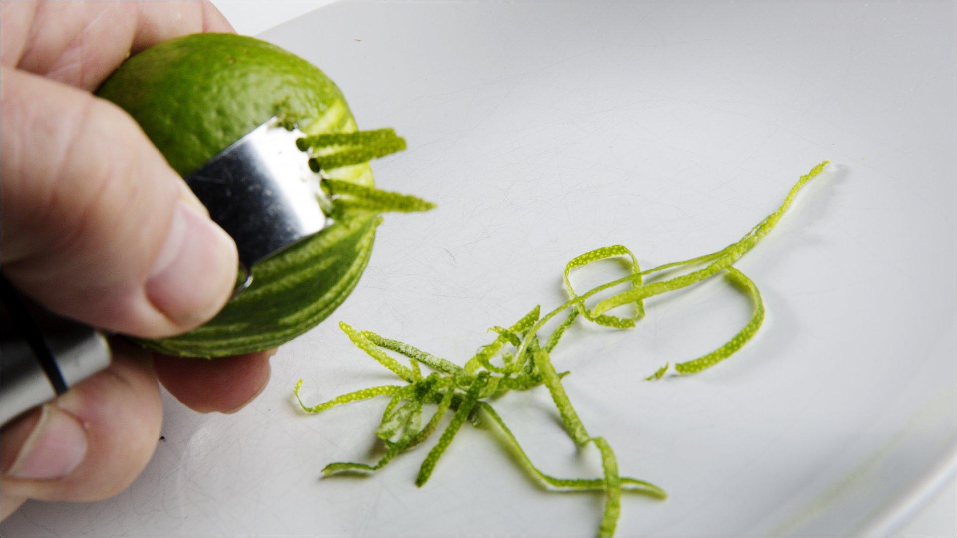 Skrubb limefruktene i renne vann, før det ytterste laget på skallet skjæres av i tynne strimler.