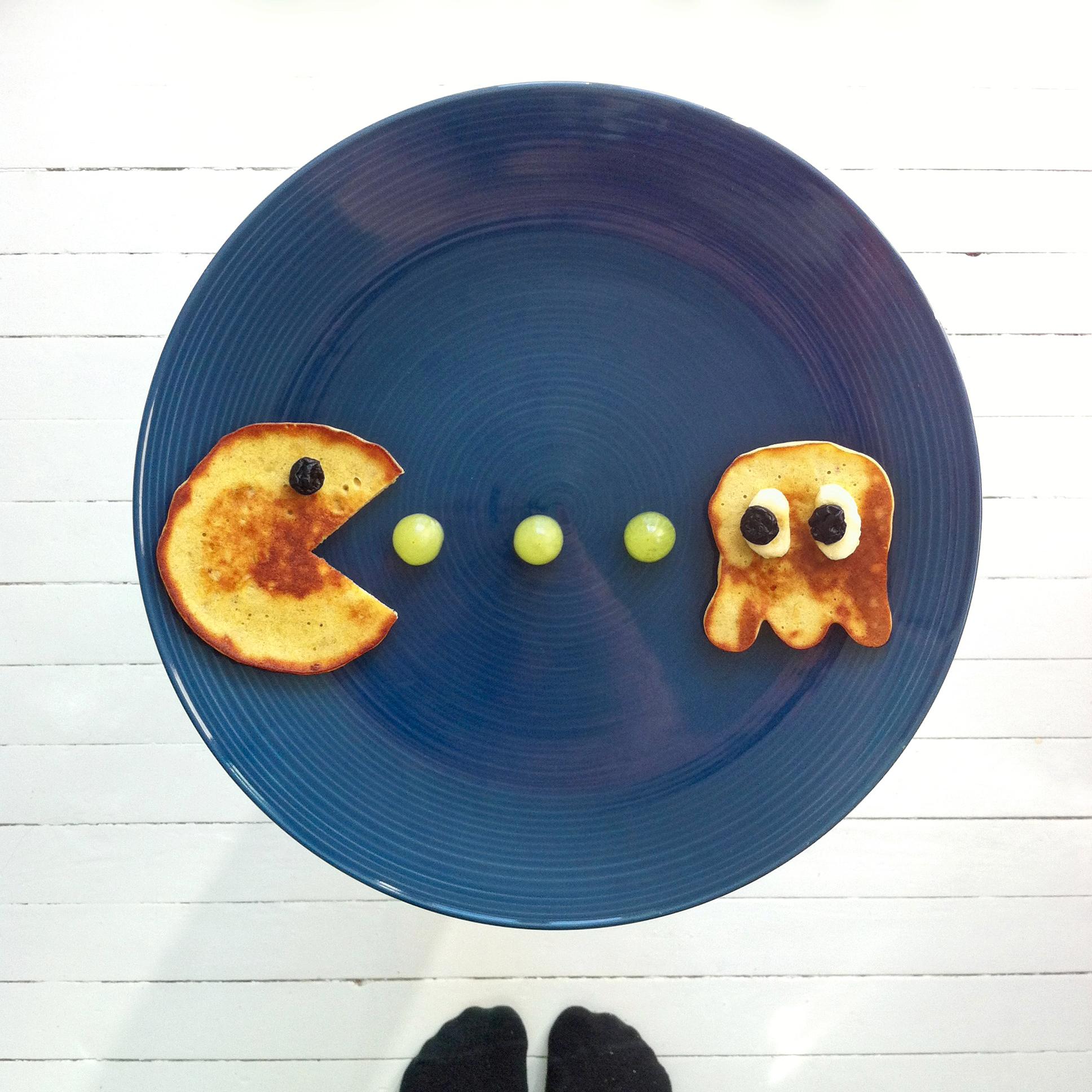 Del en bananskive i to og avrund hver halvdel litt. Legg dette på monsteret som bakgrunn for blåbærøyne. Gi Pac-man et øye også. Del grønne druer i to og legg på tallerkenen. Lag flere monstre og dekk dem med syltetøy for ekstra moro. Pac-man må selvsagt være gul. Spill i vei!