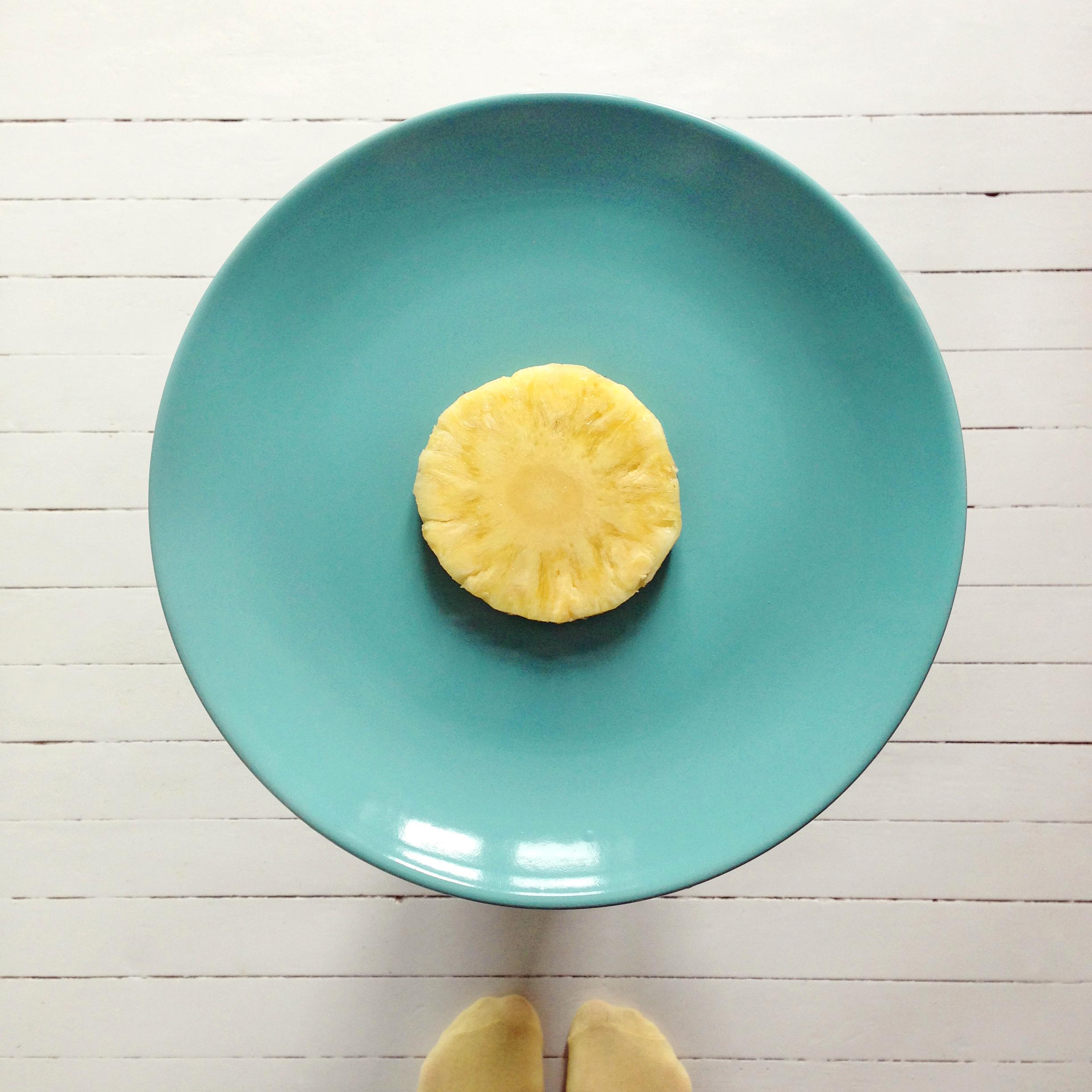 Skjær av to skiver ananas, legg den ene midt på en tallerken. Du kan gjerne kutte vekk det harde midtstykket slik at det blir en vanlig ring.