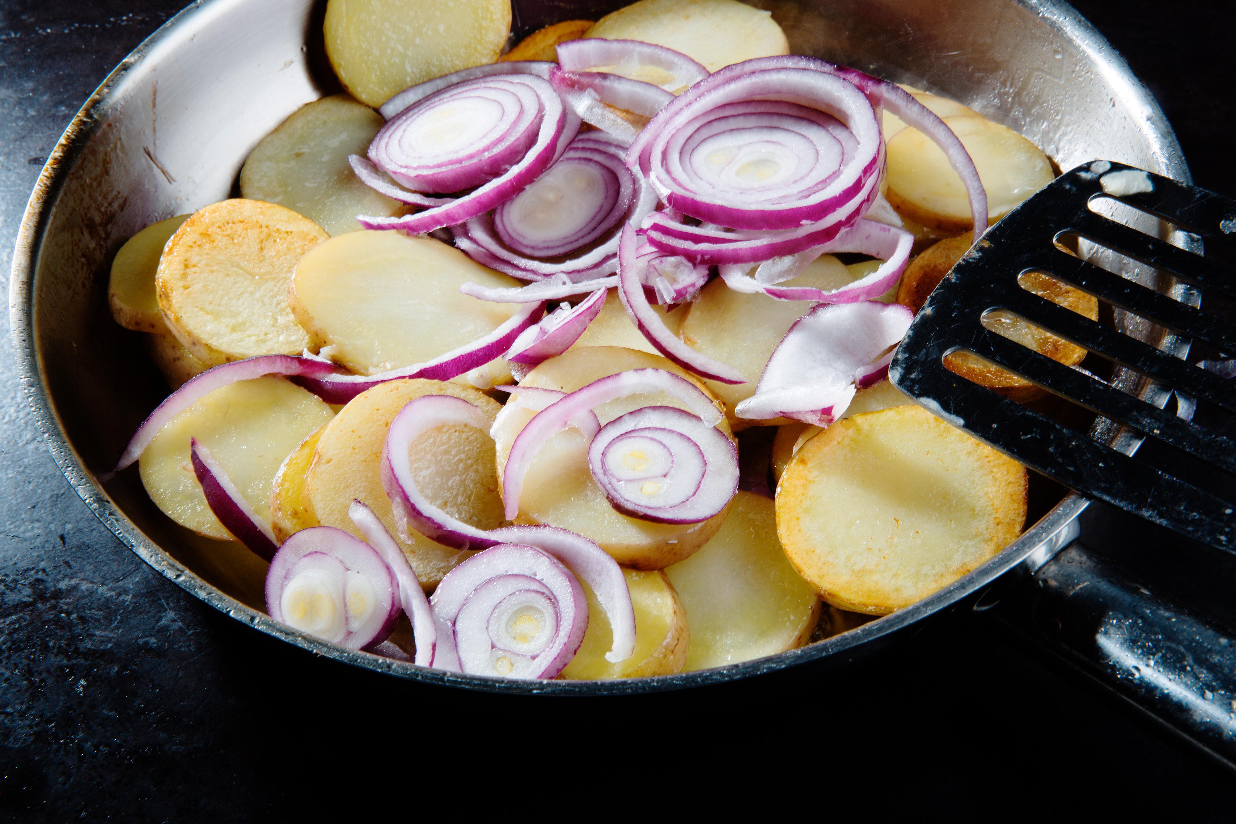 Vask potetene godt, før de skjæres opp i skiver. Varm olje i en vid panne og stek potetskivene i ca. 10 minutter. Tilsett rødløk skåret i tynne ringer, la den steke med de siste 5 minuttene. Vend potetskivene jevnlig under stekingen.