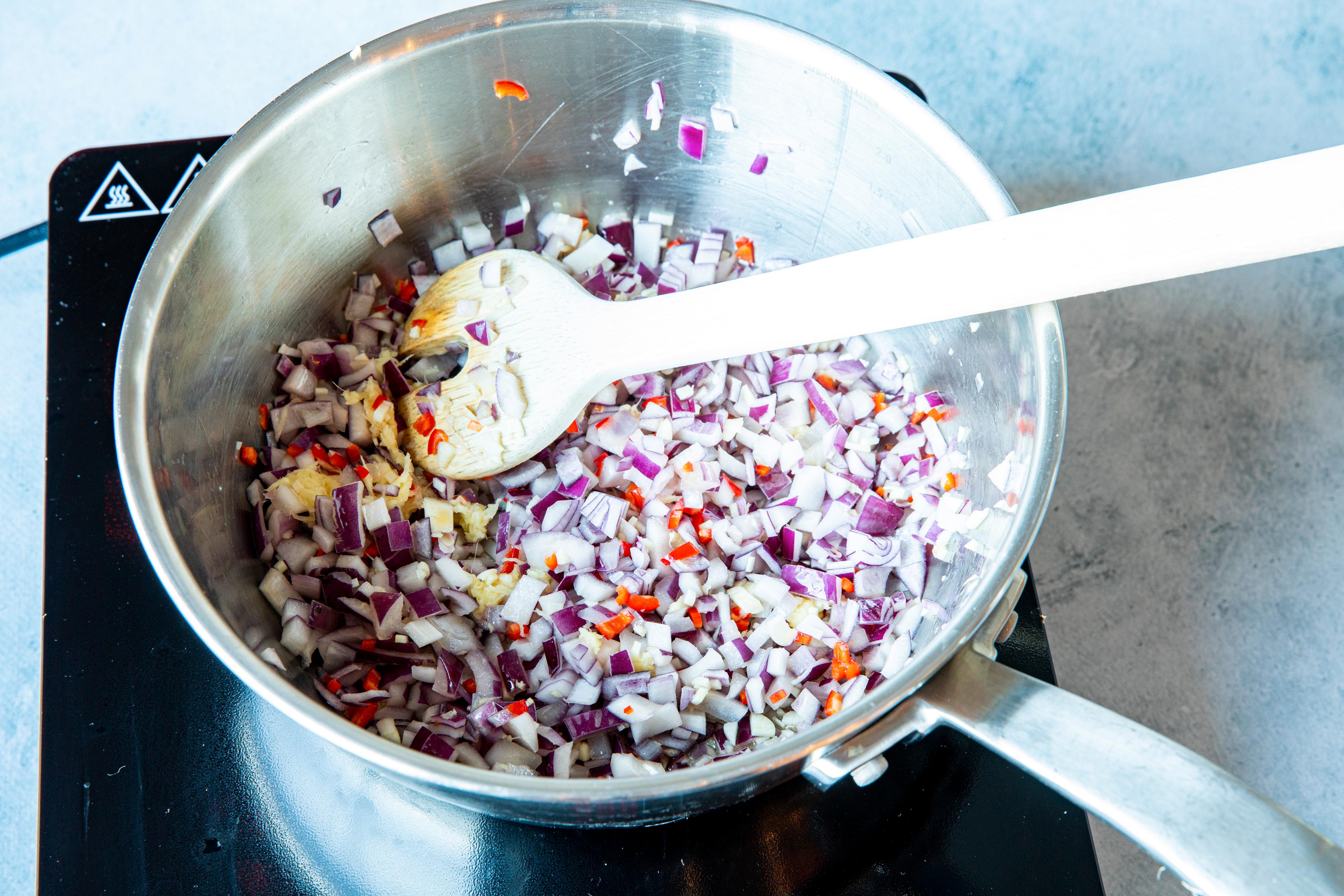 Fres en klunk olje i en mellomstor kasserolle/gryte. Fres hvitløk og løk til løken blir myk og gyllen. Tilsett ingefær og chili og la det frese videre under omrøring i et lite minutt.