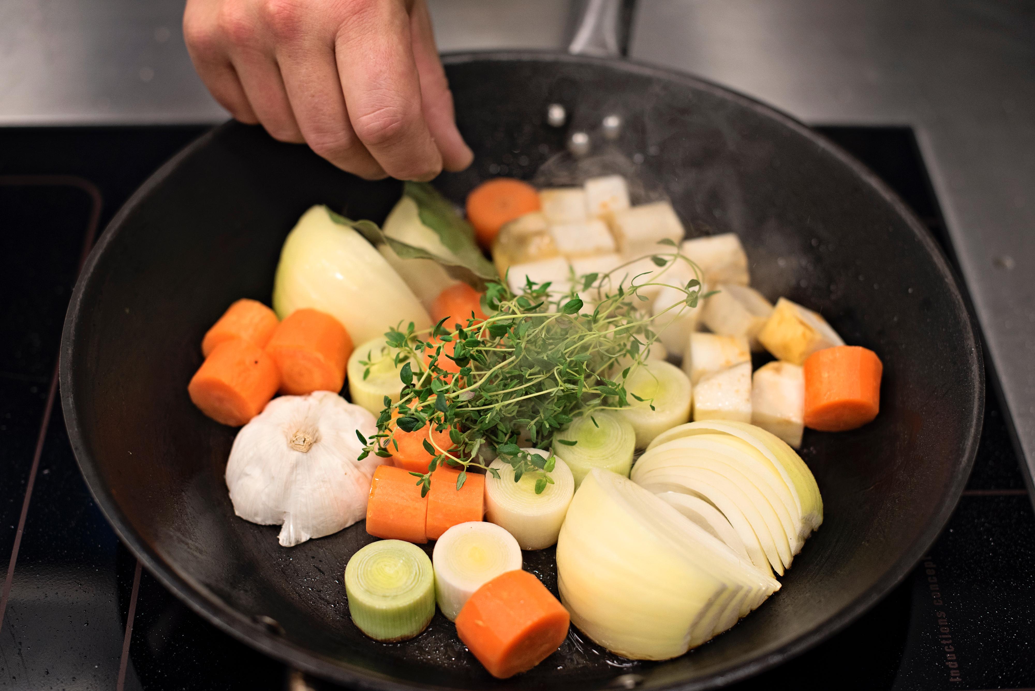 Stek alle grønnsakene i en stekepanne og ha dem i en romslig gryte sammen med beina. Kok ut stekepannen med litt av vannet og ha det over på stekebrettet/den ildfaste formen. Sørg for å få med så mye farge og smak som mulig fra brettet/formen og ha det i gryta.