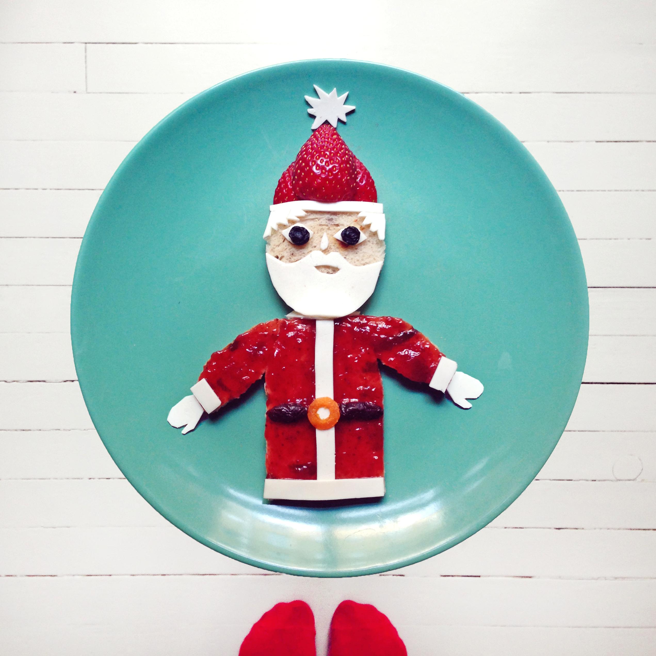 Steg 5: Kutt jordbæret i to som nisselue og dekorer med hvitostdusk. Klipp ut skjegg, hår og votter. Legg på to tørkede blåbær eller rosiner som øyne. Pynt gjerne opp med kiwi-juletrær og nyt julemåltidet!