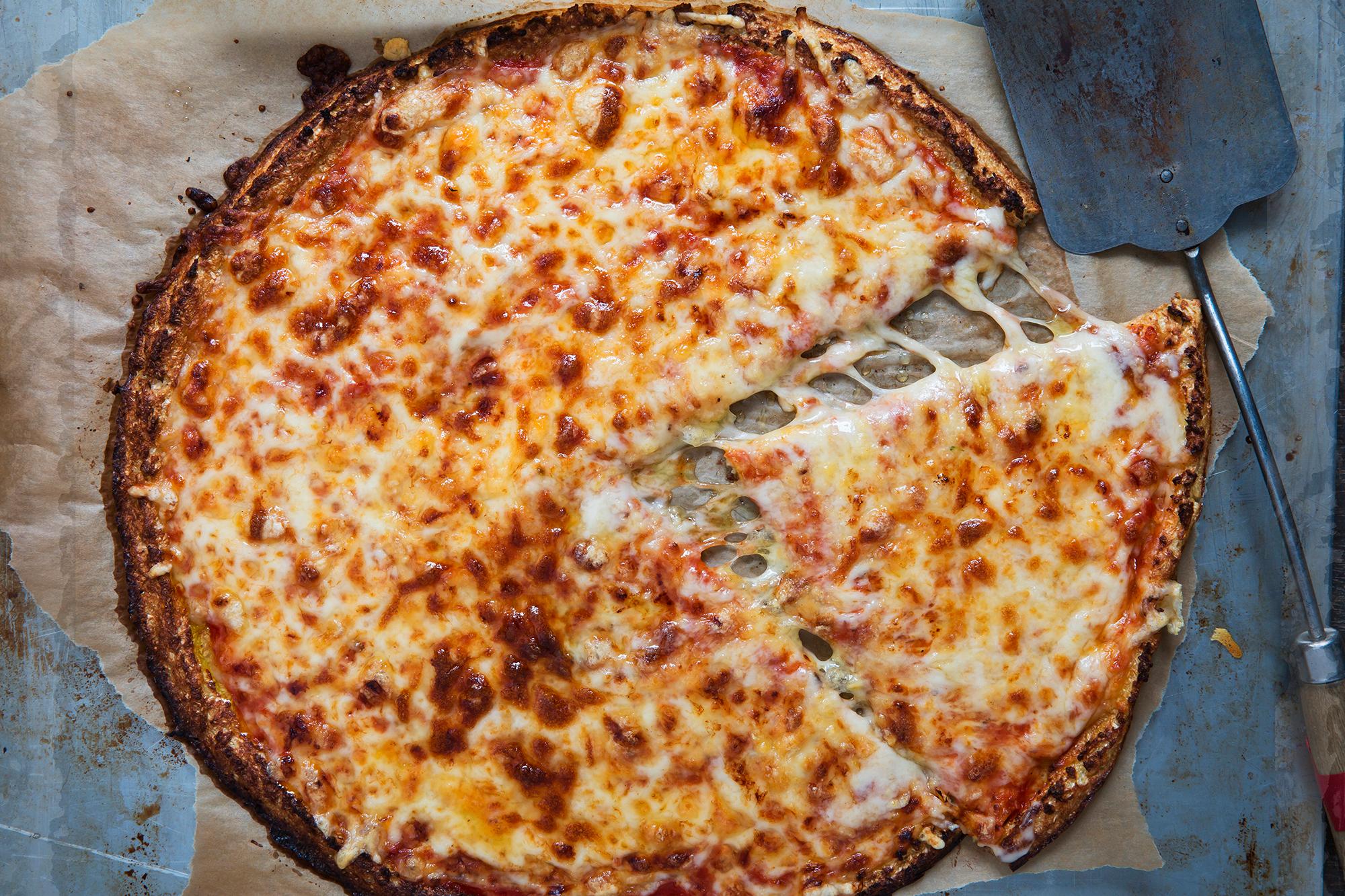Smør på tomatsaus og dryss over ost. Stek pizzaen videre i cirka 15 minutter. Del pizzaen i fire store stykker, og topp hvert stykke med spekeskinke, høvlet parmesan og basilikumblader.
