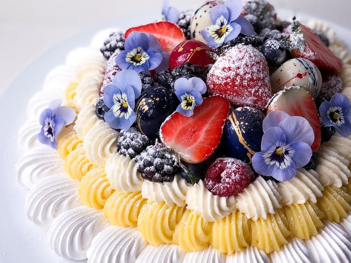 Pavlova i fint mønster med sjokolade-cremeux, fløtekrem, friske bær og spiselige blomster