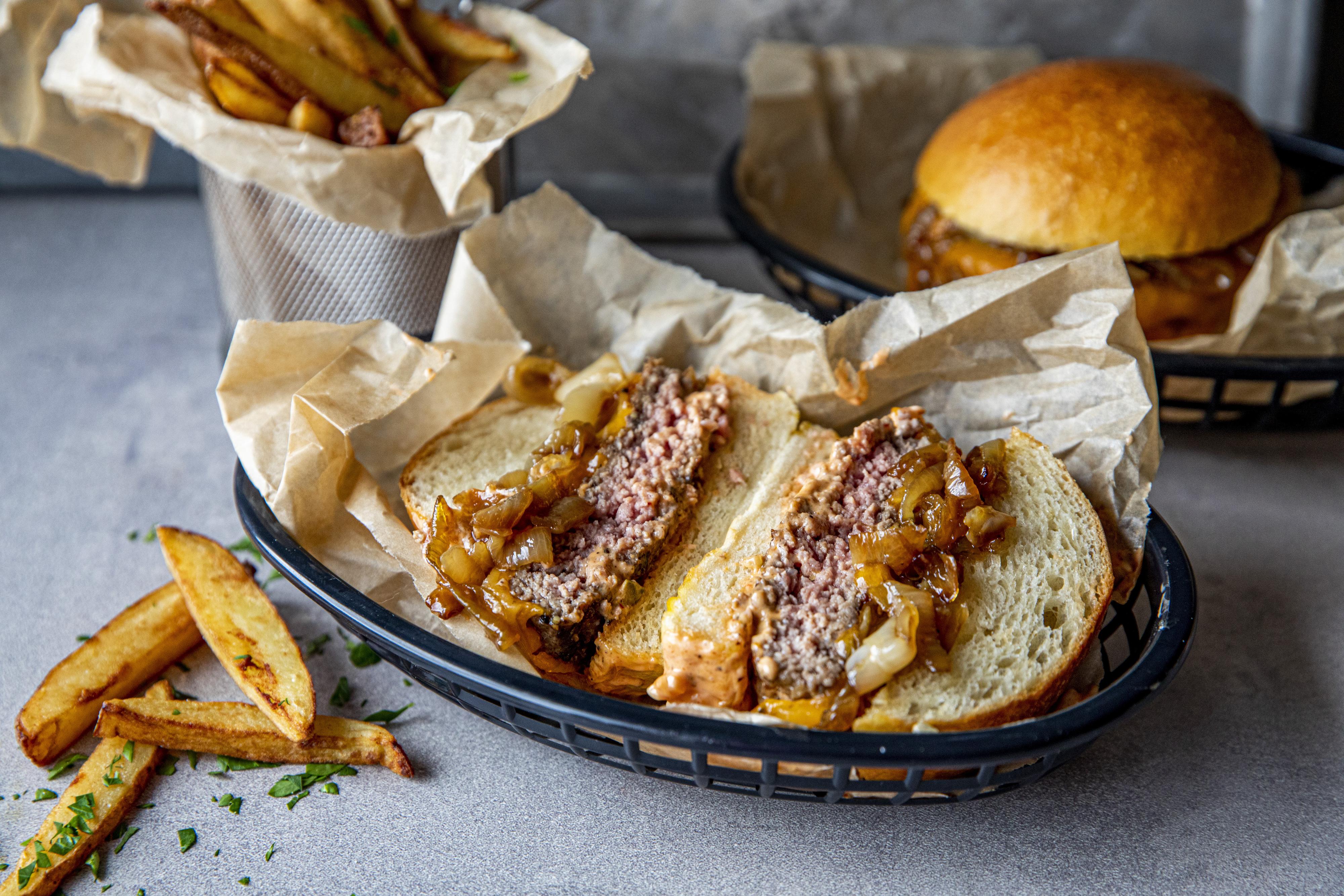 Varm brødene og legg på dressing, burger med ost, karamellisert løk og mer dressing. Serveres med fries.