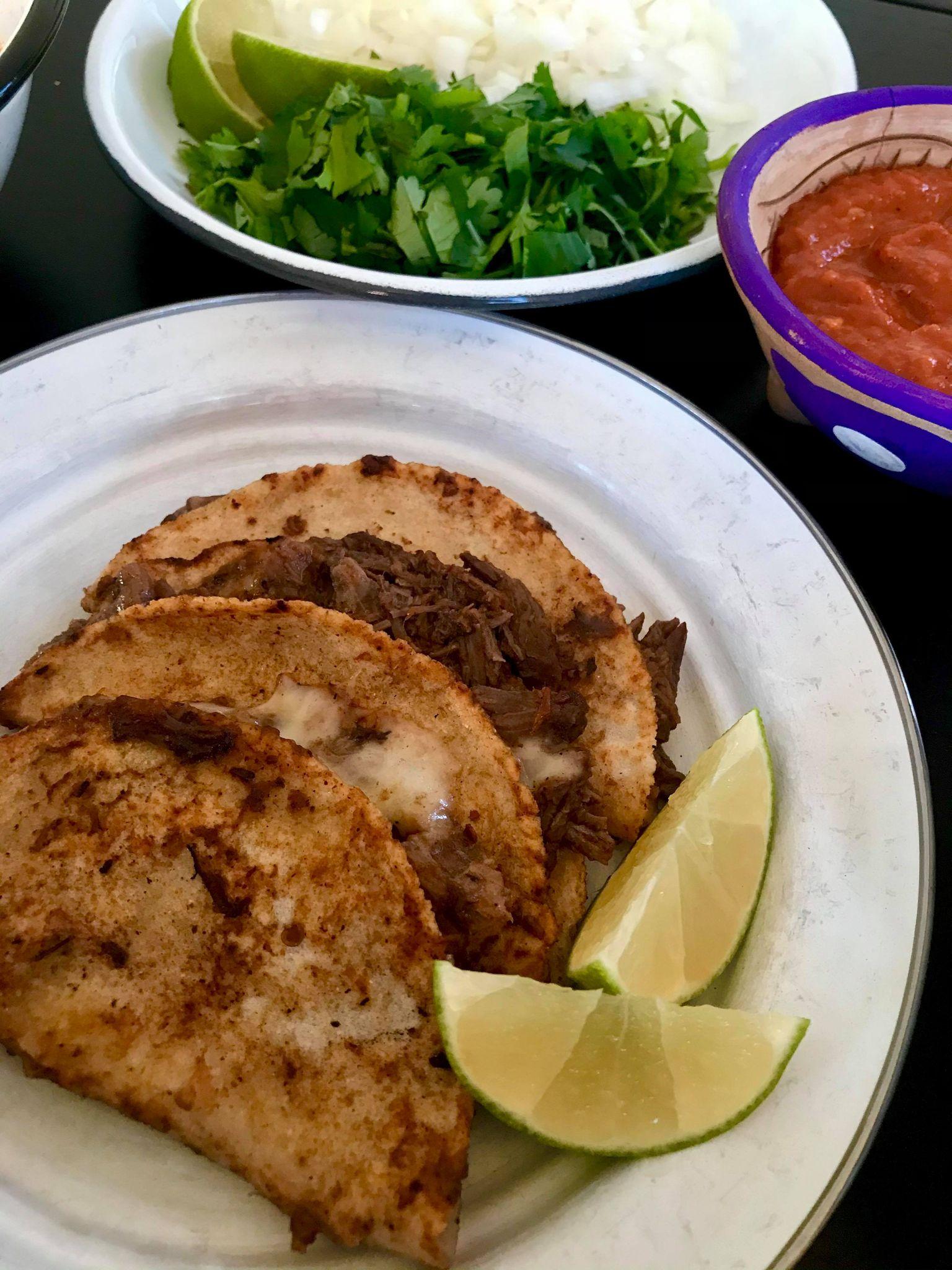 Quesotacos med consommé ved siden av der man dipper tacos i kraft: Hell litt olje i en varm panne på middels høy varme. Ta kjøtt ut av kraften, og legg det i en bolle. Du skal dyppe tortillaen først i sausen. Deretter lager du en taco med både ost og kjøtt. Pass på å legge ost først på tortillaen og så på kjøttet. Brett sammen og legg tacoen i stekepannen. Det beste å bruke er queso Oaxaca. Hvis du ikke finner den, kan du bruke en vanlig gulost som smelter bra. La osten smelte, og snu tacoen. Hell på ekstra saus og la den steke til sausen fordamper.  Fyll tacoen med garnityr, og server med consommé som du kan dyppe i.  