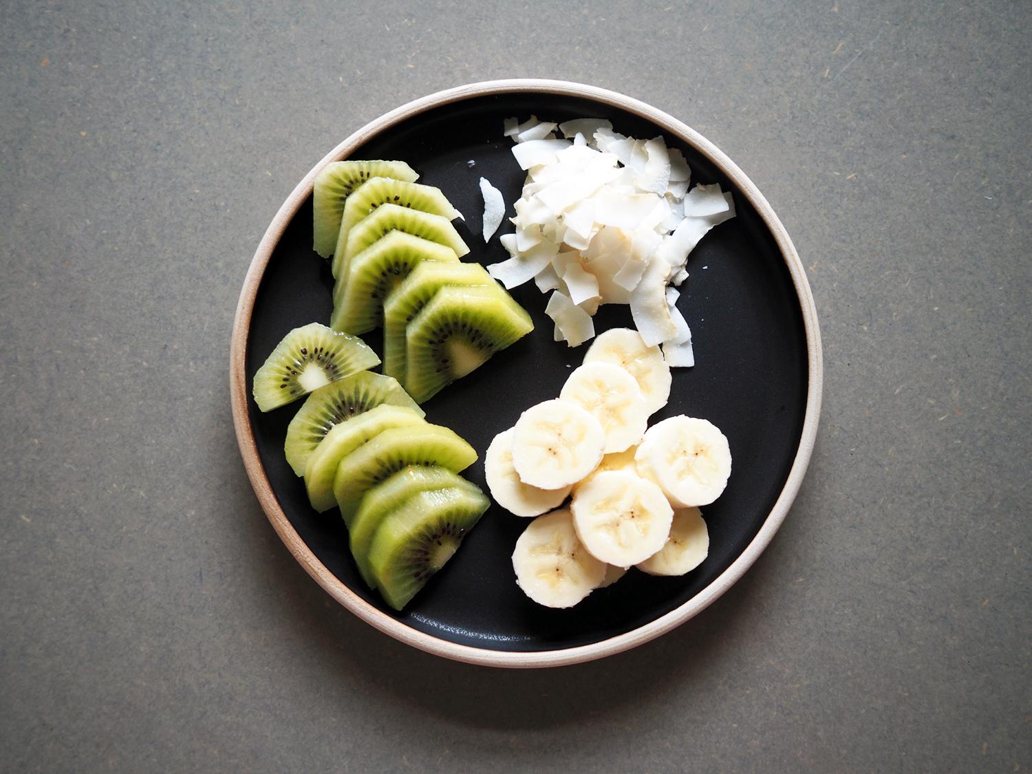 Kutt opp kiwi og banan, eller den frukten du selv vil toppe med. Her har jeg også brukt litt kokosflak for god crunch.