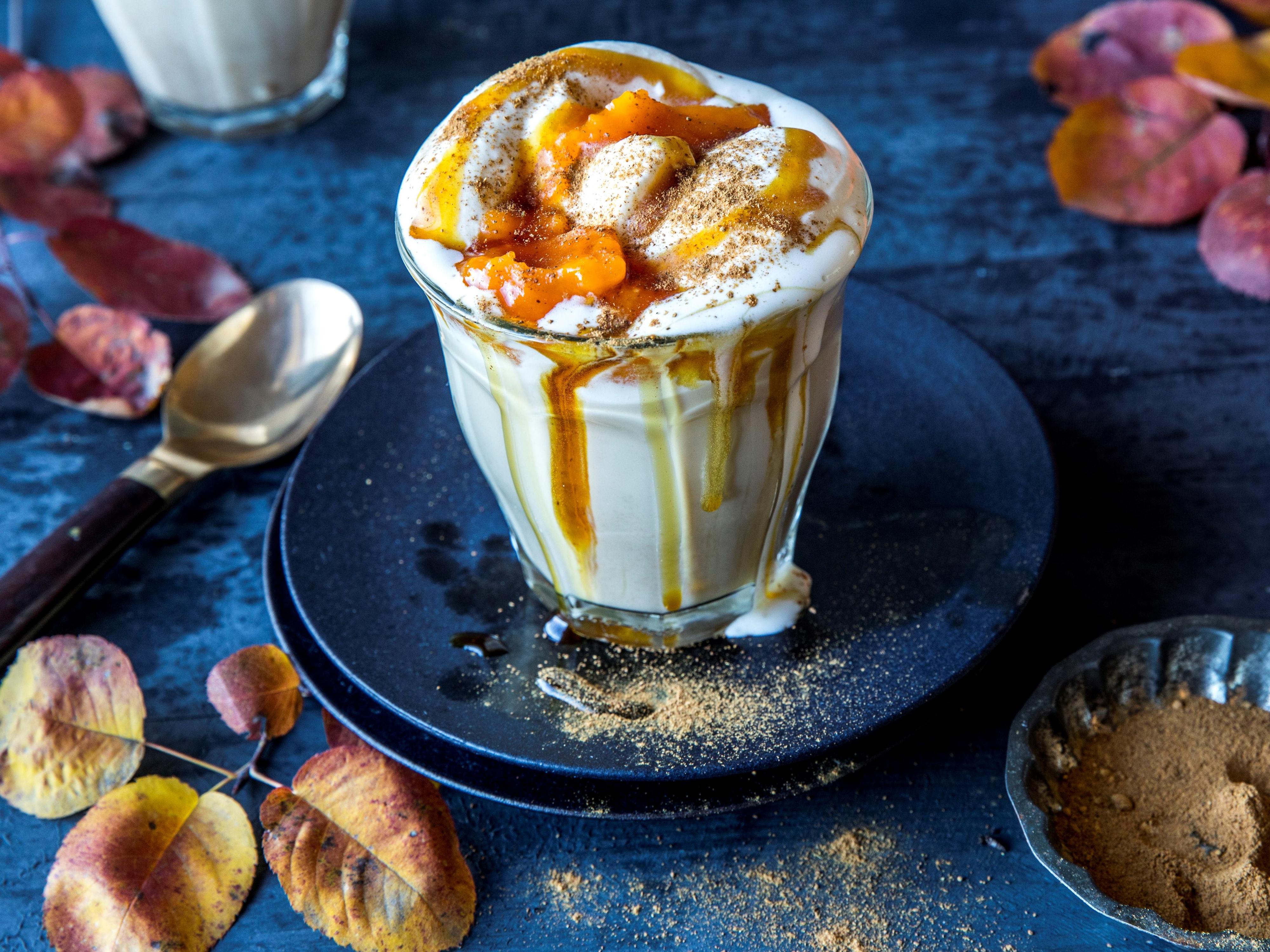 Pumpkin spice latte i glass toppet med pisket krem og karamellsaus
