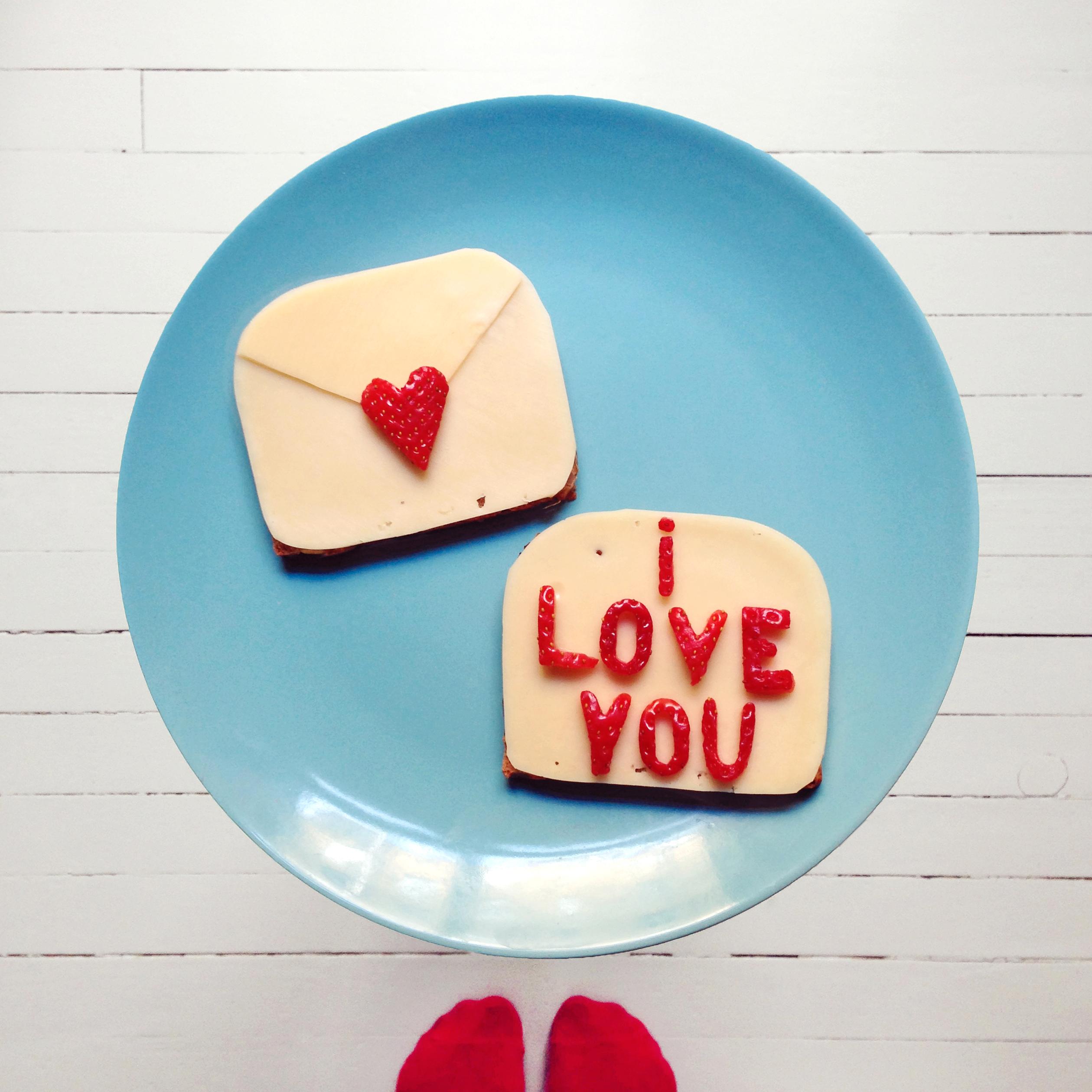 Fest på hjertet på konvolutten og legg den ønskede kjærlighetsbeskjeden på «brevarket». Pynt gjerne med rester av ost og jordbær ellers på tallerkenen. Server frokosten i sengen og håp på fordelaktig svar.