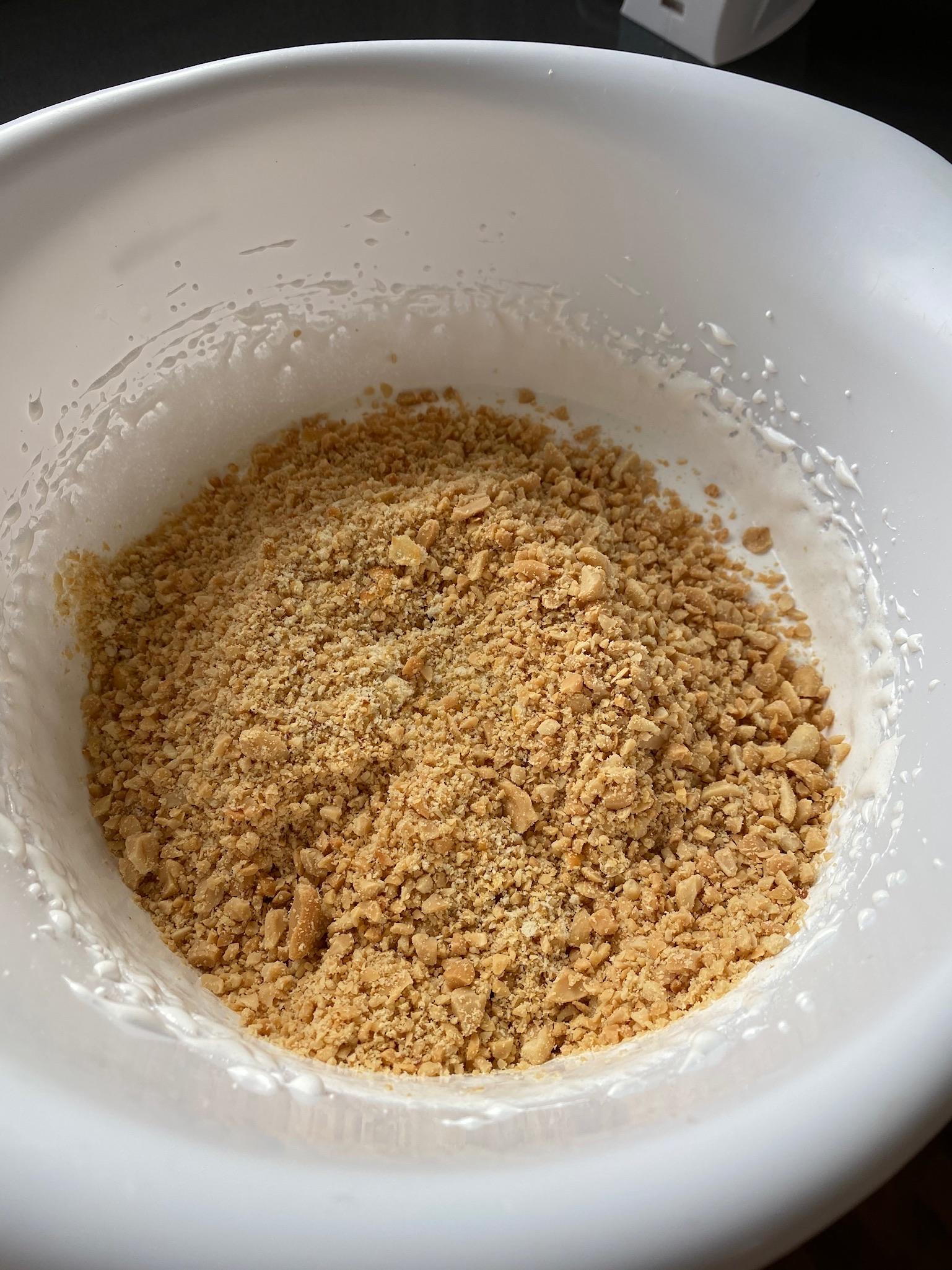 Stivpisk eggehviter og sukker. Ha i finhakkede peanøtter og Ritz-kjeks som smuldres.