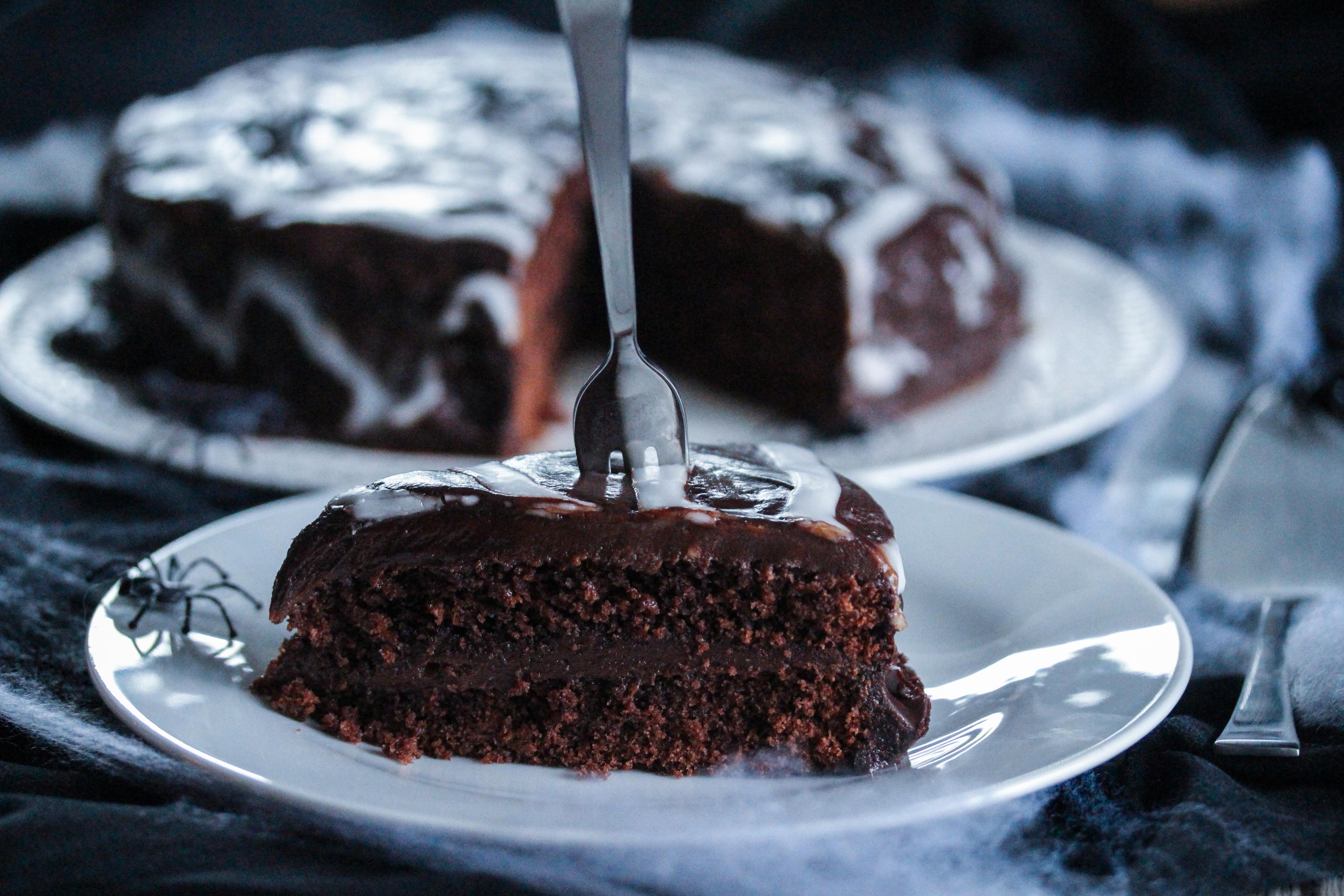 Smør sjokoladeganachen over toppen av kaken. Sprøyt deretter melisglasuren på kaken i et spiralmønster. Bruk så en tannpirker og dra den gjennom spiralen, fra midten og ut til kantene, så du får et spindelvev-mønster. 