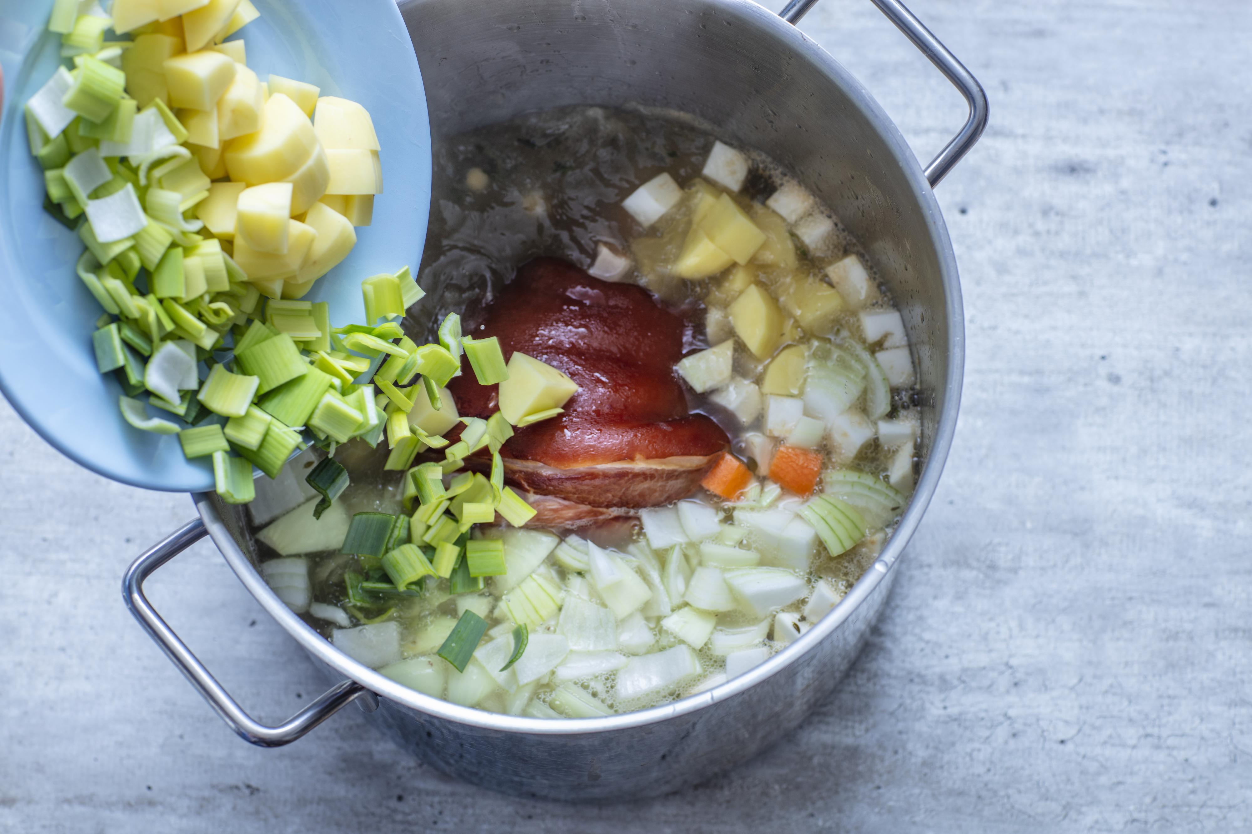 Ha grønnsakene over i kjelen og la det hele småkoke videre i en times tid uten lokk (eller med lokket halvveis på), tilsett en skvett vann underveis hvis nødvendig. Kok til ertene er helt møre. 