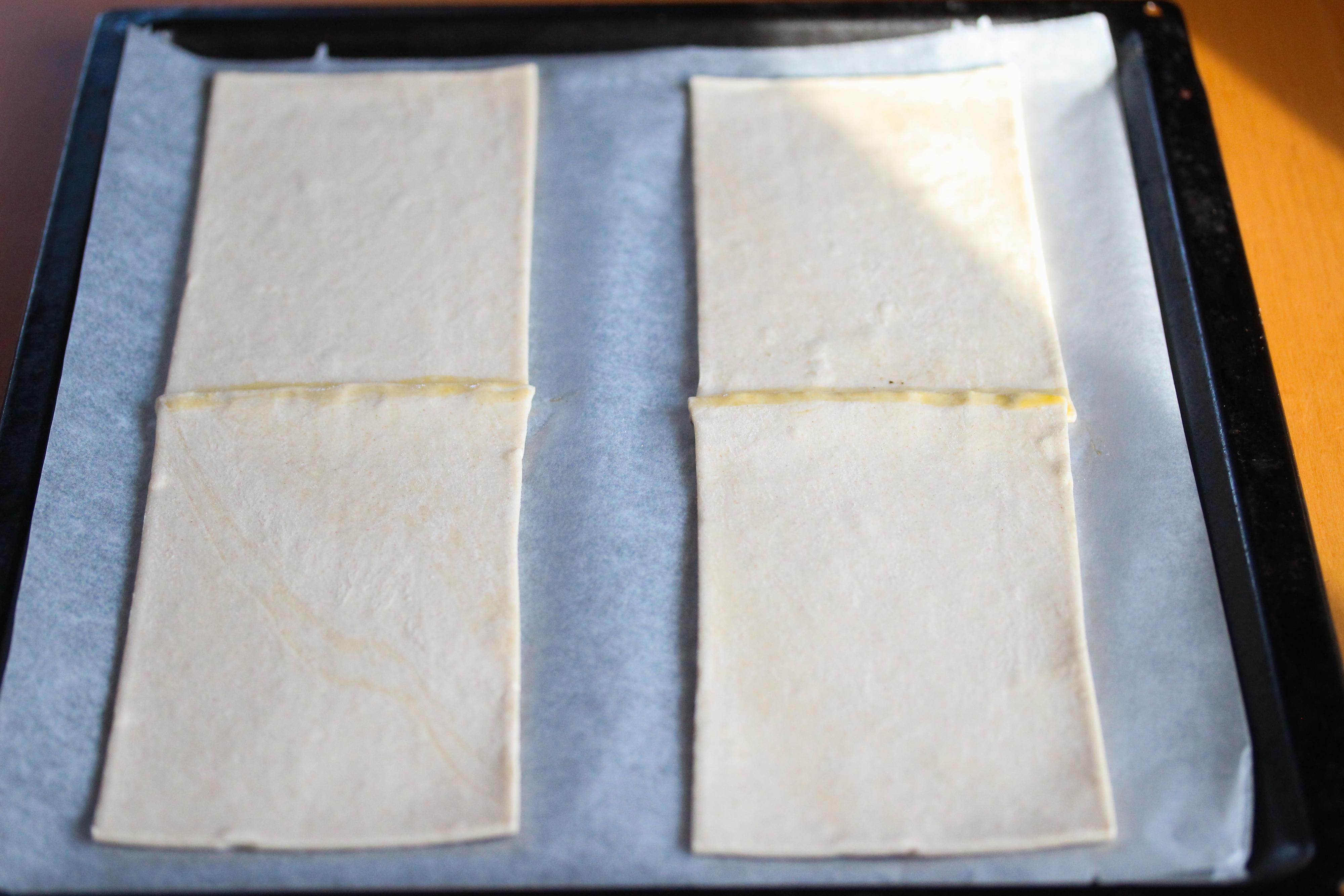 Finn frem en stekeplate og dekk den med bakepapir. Legg butterdeigsplatene etter hverandre to og to, lett overlappende, slik at du får to lengder. Pensle med litt egg i skjøtene.