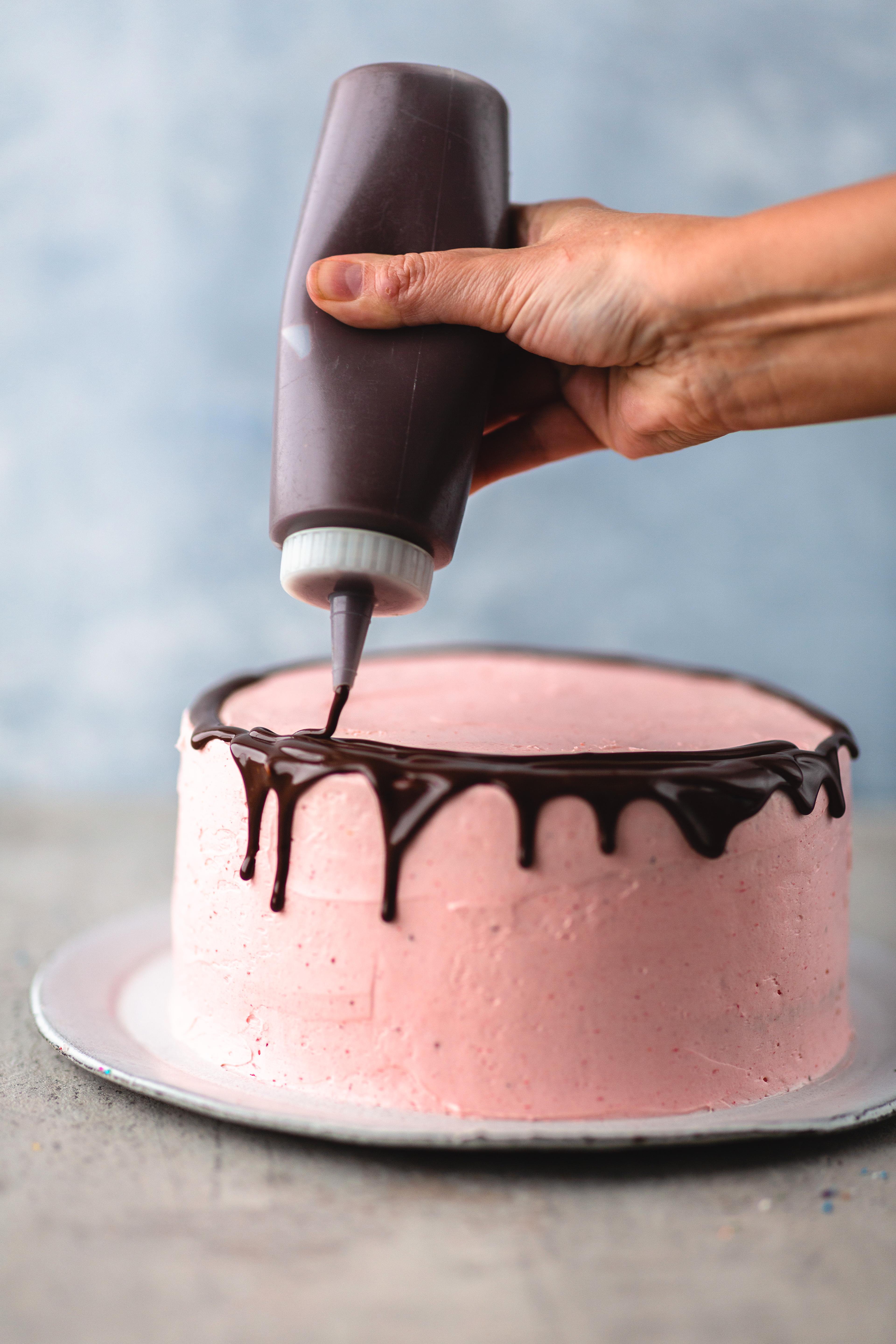 For at det skal bli enklere å helle sjokoladen langs med kanten av kaken, kan du fylle den over på en spruteflaske, desilitermål eller en liten mugge. Hell sjokoladen langs med kanten på den avkjølte kaken og fortsett med toppen. 