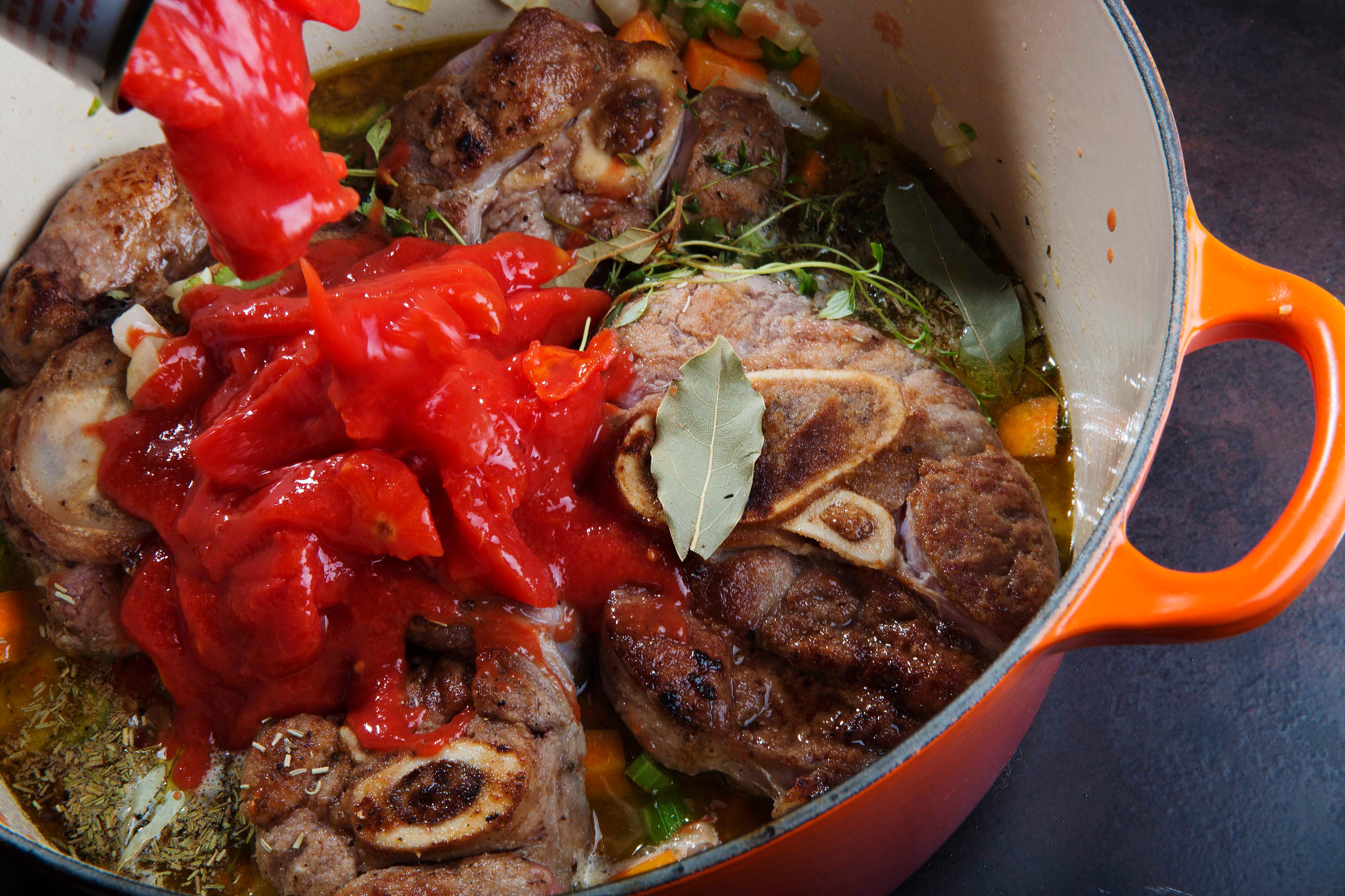 Legg i kalveskankene og tøm over hermetiske tomater. Kok opp og la kjøttet syde under lokk på svak varme et par timer til kjøttet er mørt.