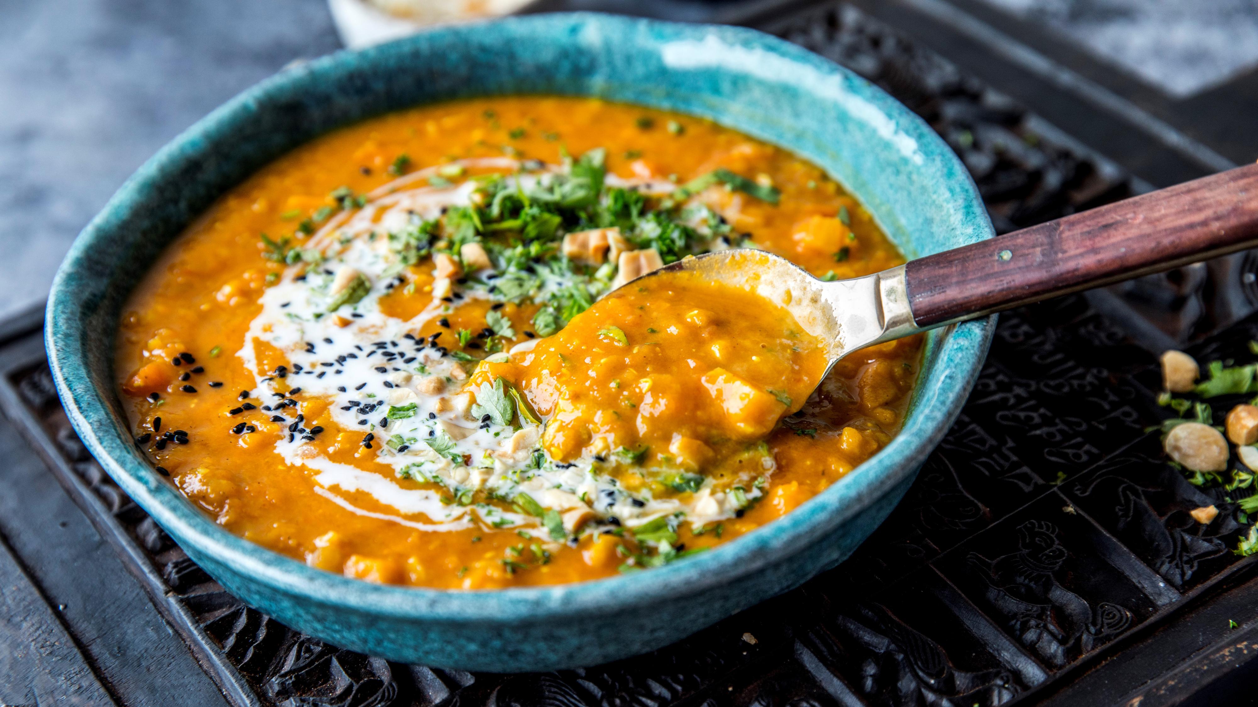 Mulligatawny-suppe i en blå skål, med friske urter på toppen.